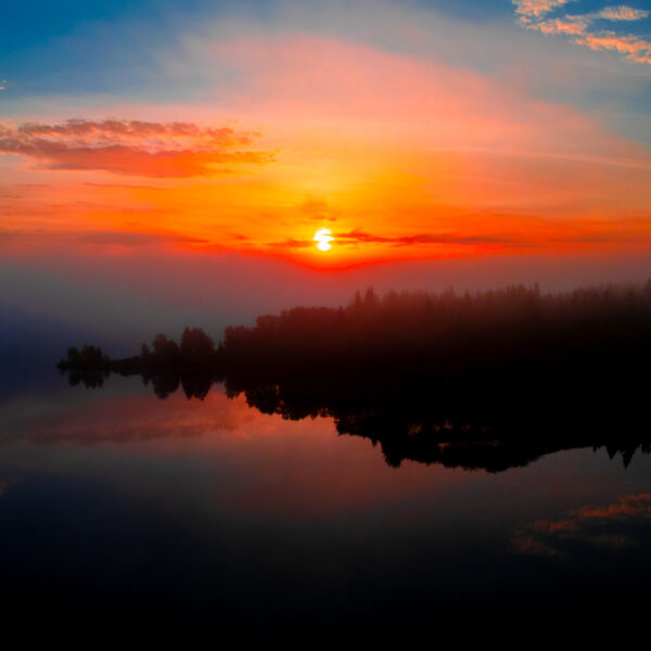 Solnedgang over sjø og skog